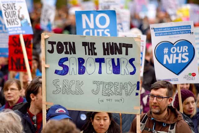 Protestors on a Save the NHS march with banners and posters.