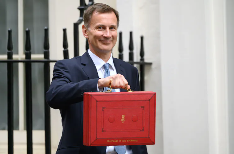 Jeremy Hunt, the British chancellor, holds up a red briefcase.