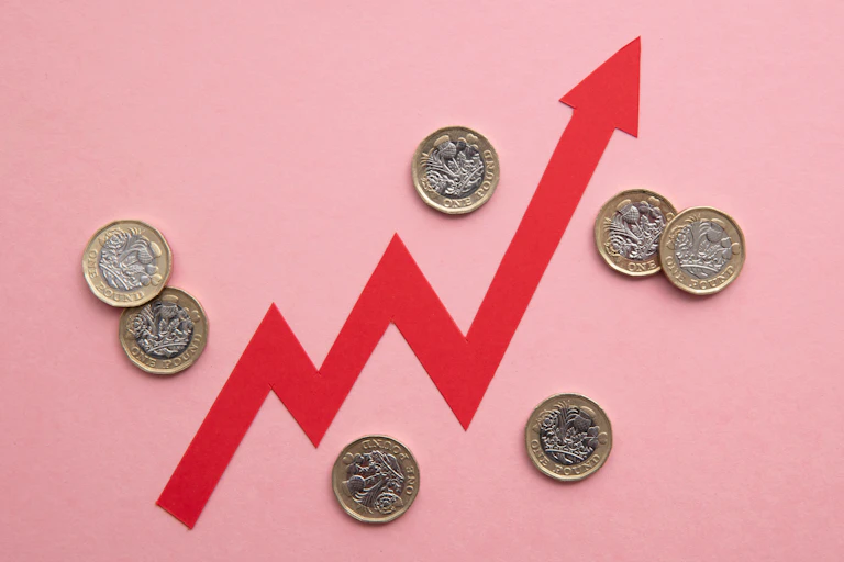 A red arrow jagging up and down, surrounded by pound coins, all on a pink background.