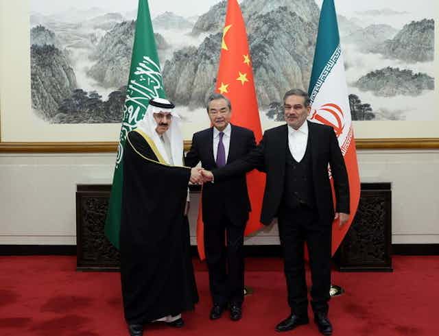 World leaders shake hands in front of flags of Saudi Arabia, China and Iran