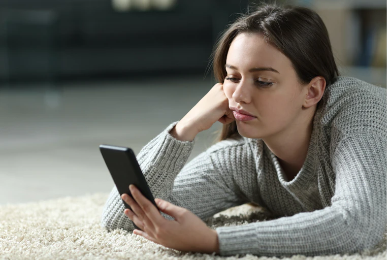 Une jeune femme boudeuse regarde son téléphone