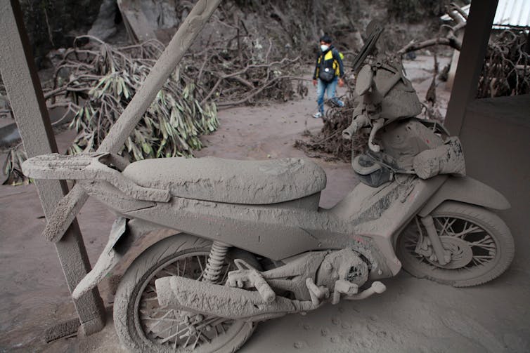 A motorbike, and the ground around it, covered in ash.