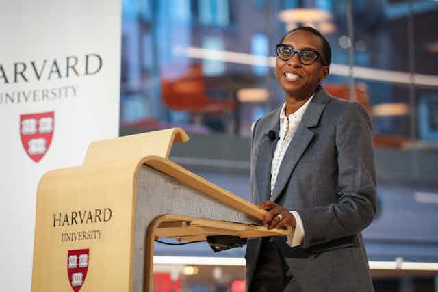 Woman stands at a lectern with Harvard University name and logo on the front