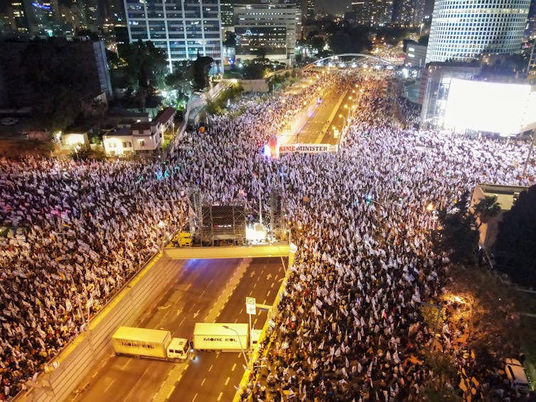 Miles de personas marchan en la noche en las calles.