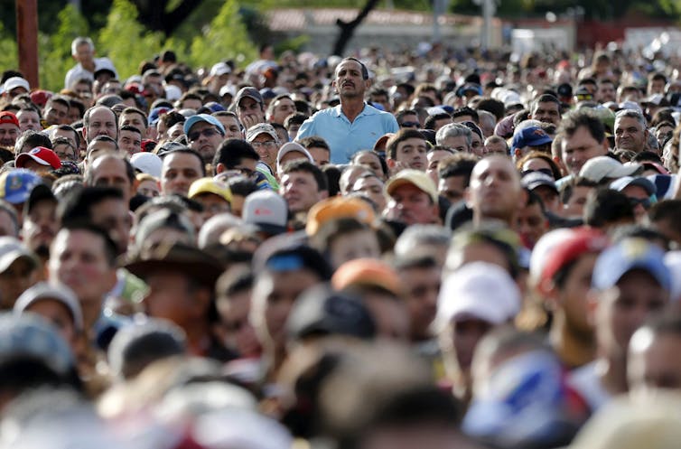A man in a blue shirt is seen in a sea of people.