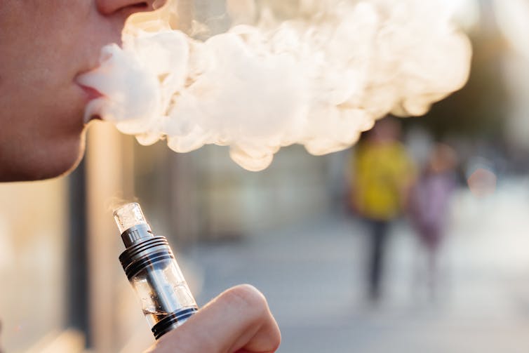 person breathes out vapour from e-cigarette