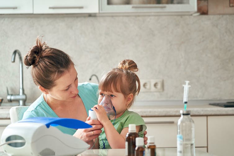 A women helping a young child with an inhaler