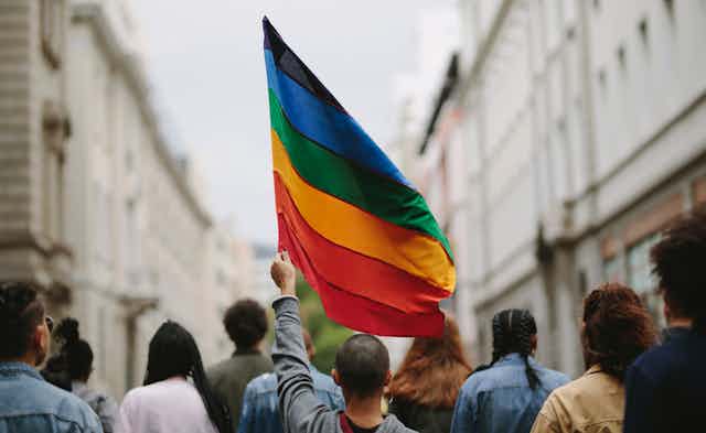 Person holding a rainbow flag at a protest march