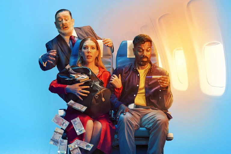 Couple sitting in airline seats holding a bag with money tumbling out