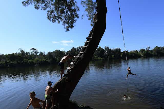 Young people jumping into the river on a hot day