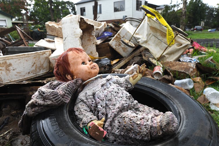 flood-damaged doll and other items with house in background