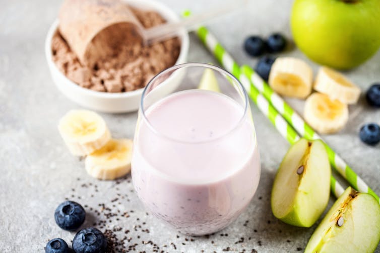 selection of fruits, chocolate powder and milky drink on benchtop