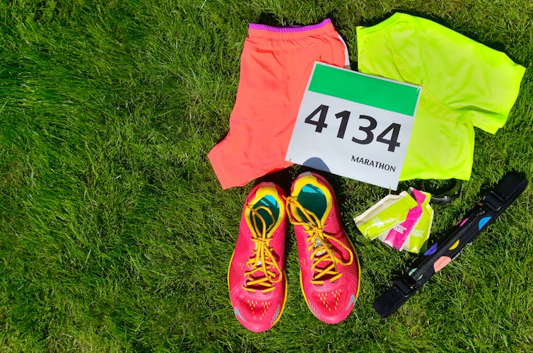 Runners kit including clothes, shoes, energy gels and competitor bib on grass