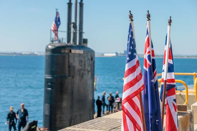 US, UK and Australian flags in front of a submarine