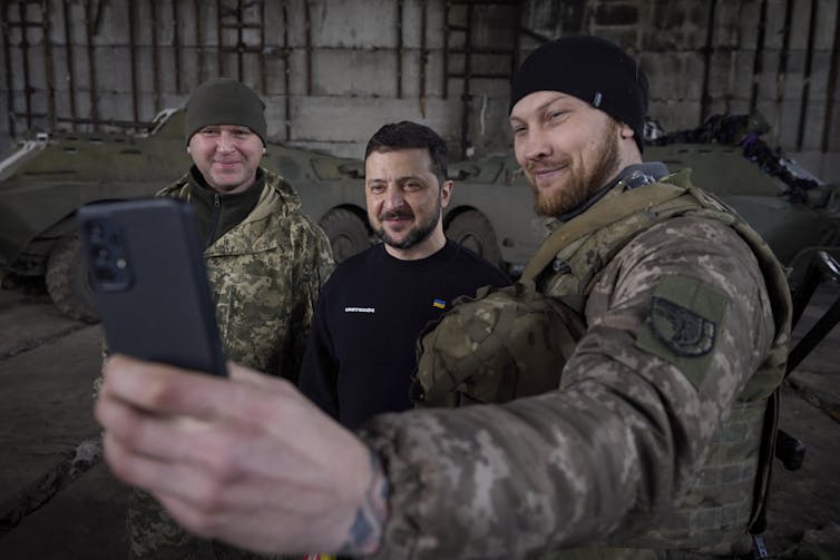 Ukrainian president Volodymyr Zelensky poses for selfies with men in army uniforms.