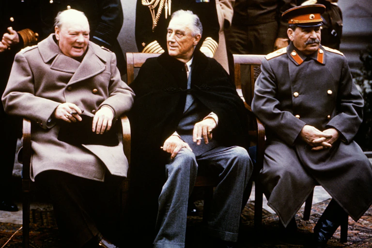Three men, Winston Churchill, Franklin D Roosevelt and Joseph Stalin, sitting on chairs and talking.