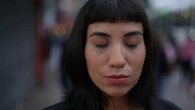 Woman closing eyes in street.