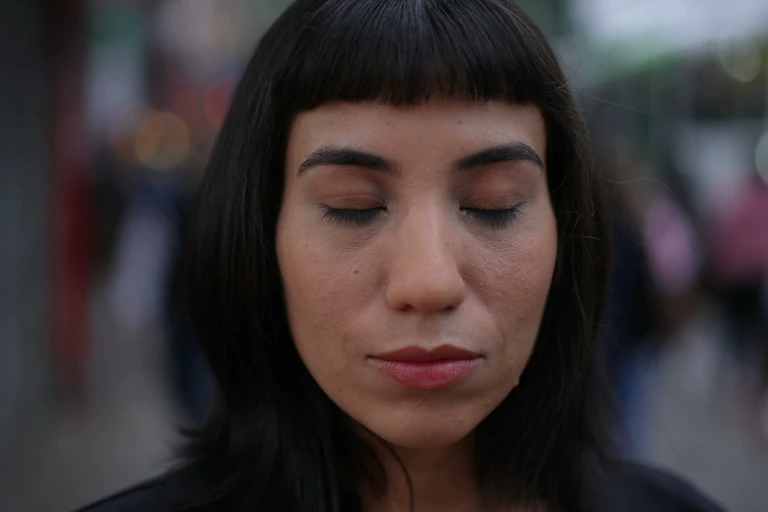 Woman closing eyes in street.