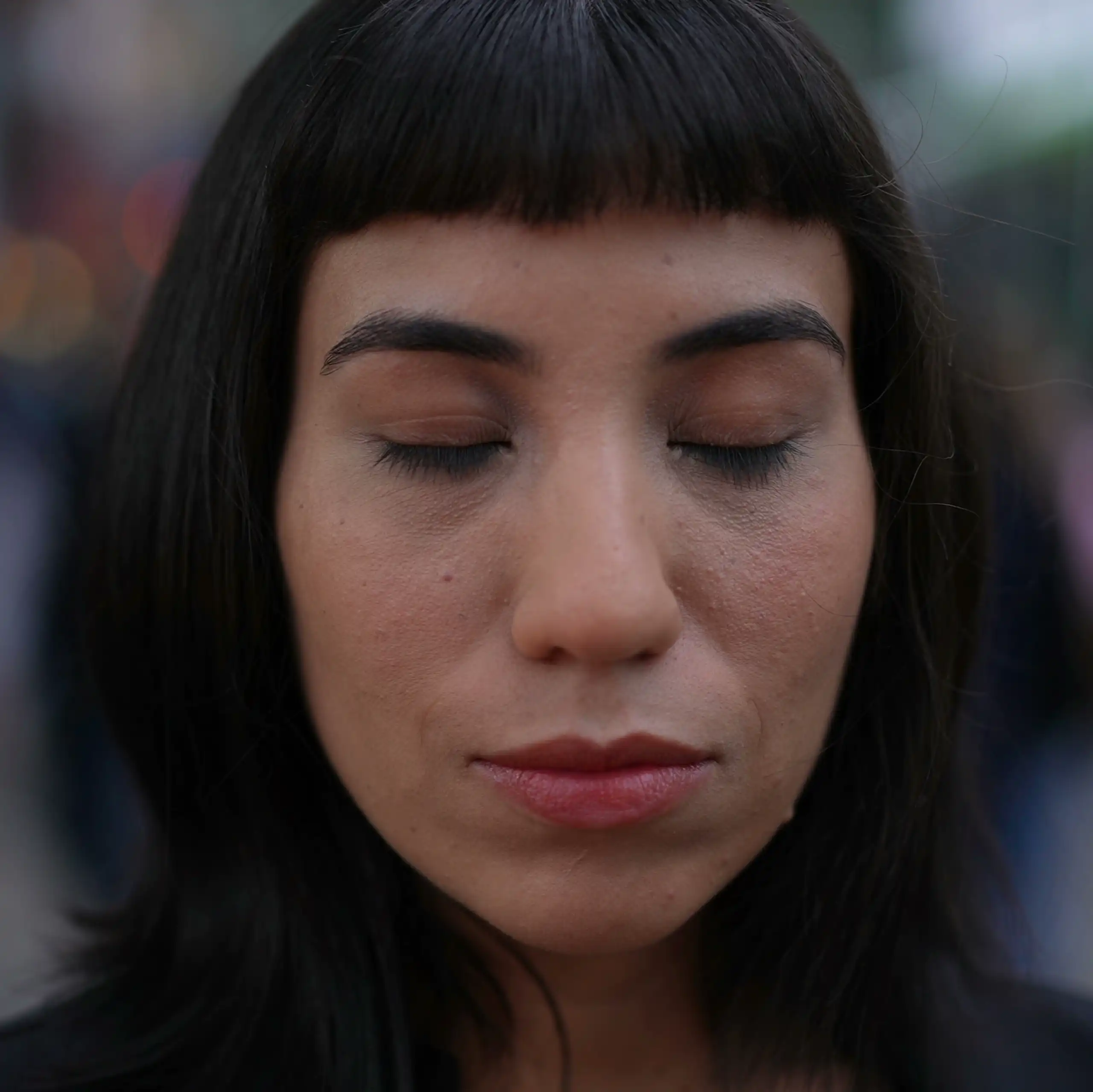 Woman closing eyes in street.