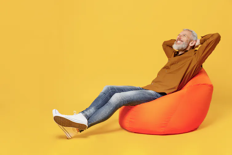 A man sitting on an orange beanbag doing the catapult body language position.