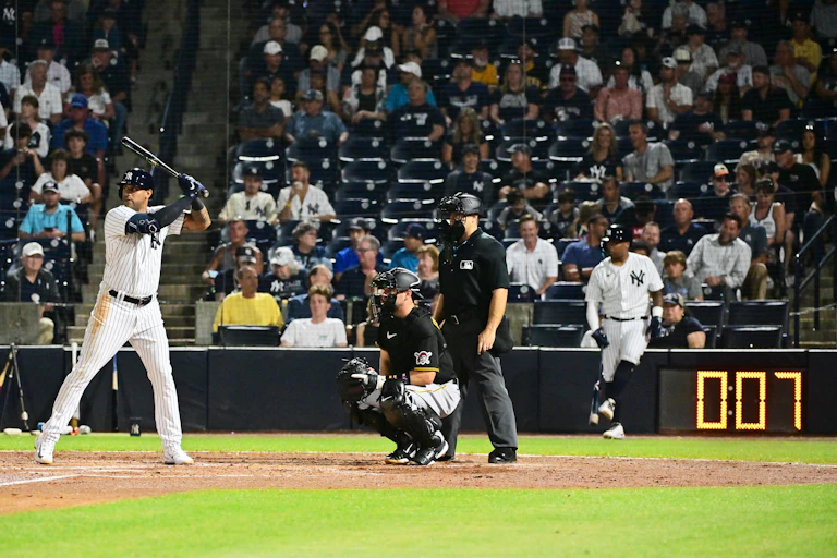 Baseball player stands at the plate with a digital pitch clock in the background.