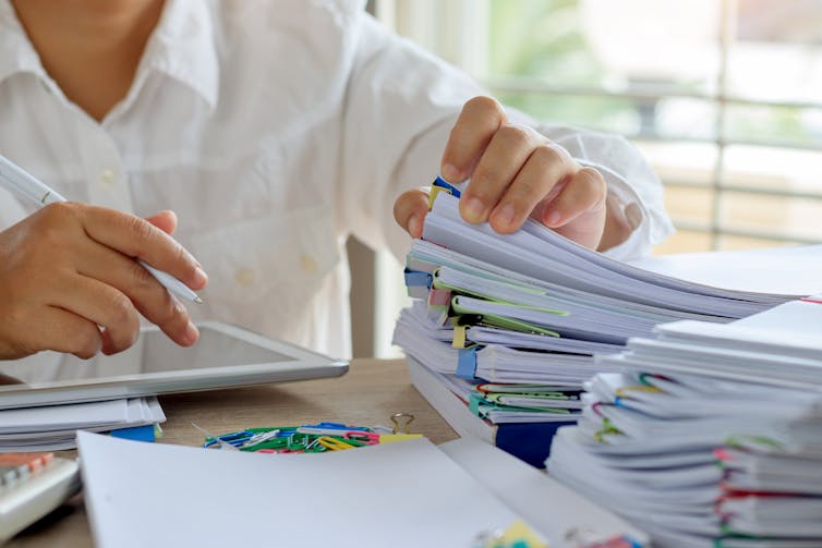 Teacher marking work, stacks of papers