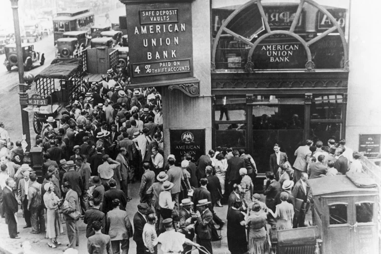 People in the early 20th century line up outside a bank.