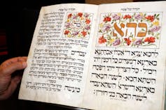 A close-up of a large book with brightly illustrated letters written in Hebrew