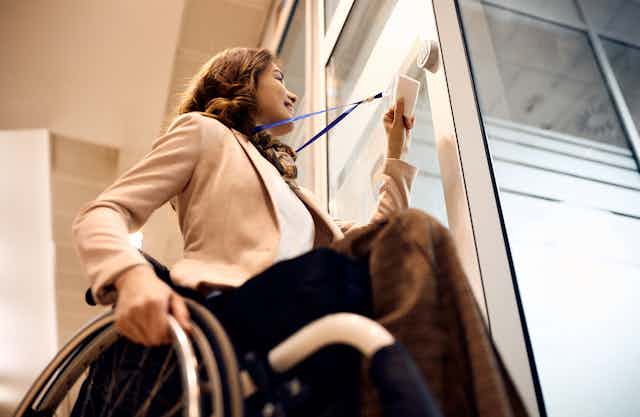 woman in wheelchair uses swipe card at door