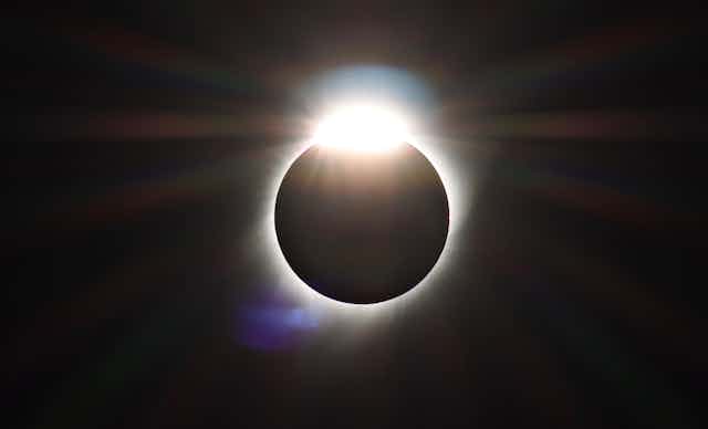 A black circle with white glowing edges and a glowing oval at the top, resembling a diamond ring