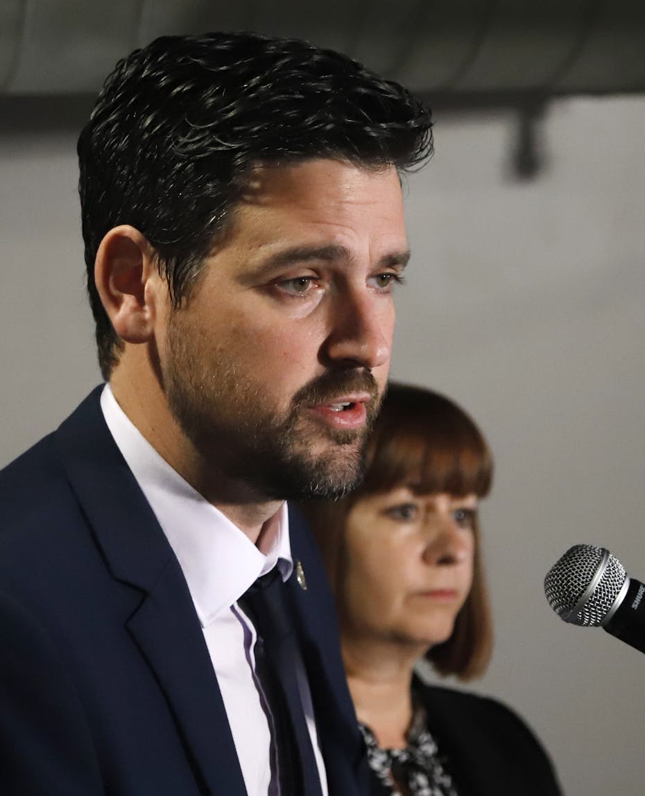 A man in a dark suit speaking into a microphone.