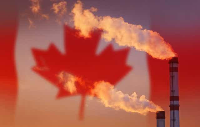 Smoke pouring out factory chimney with th Canadian flag in the background
