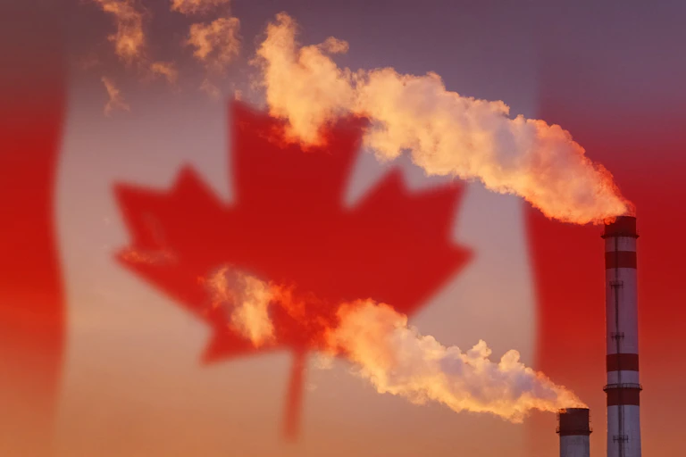 Smoke pouring out factory chimney with th Canadian flag in the background