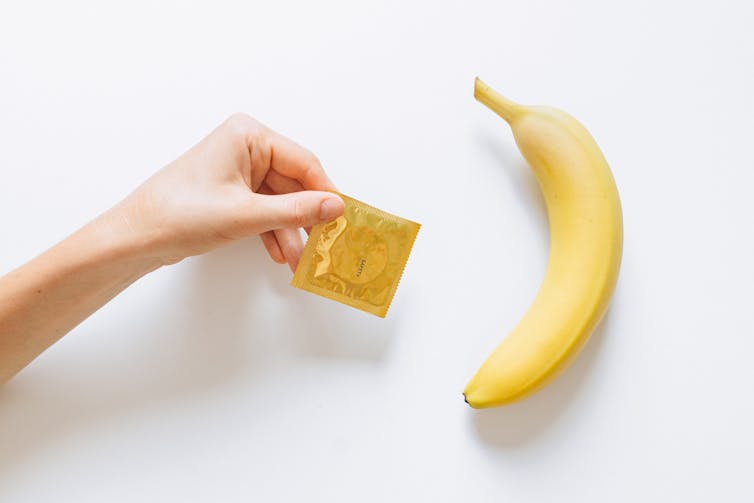A condom in a packet, next to a banana.