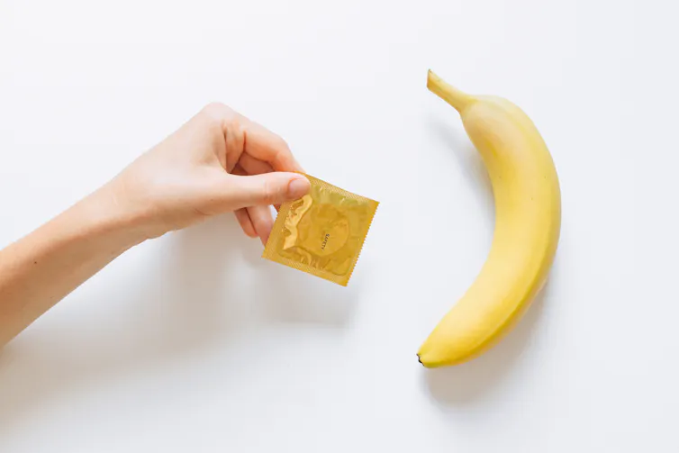 A condom in a packet, next to a banana.