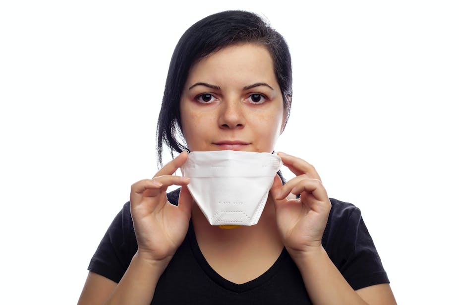 Une jeune femme enlève son masque FFP2