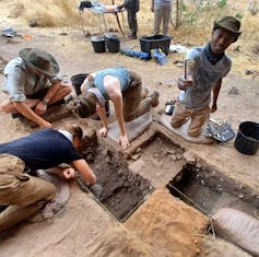 Field team member Siphesihle Kuhlase shows a broken bangle while others remove deposit in search of artefacts.