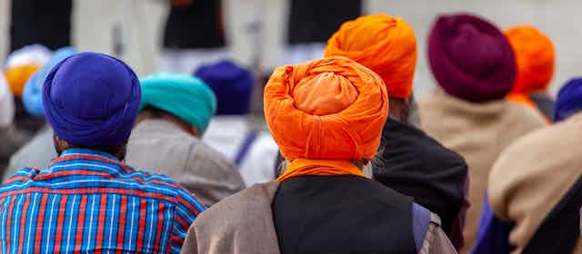 A view from behind of Sikh men wearing an array of colourful turbans. 