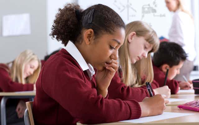 Children in uniform in class writing
