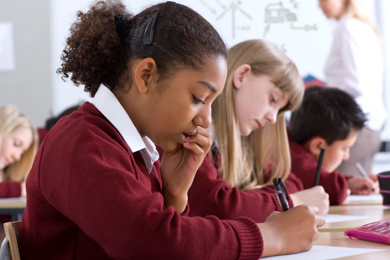 Children in uniform in class writing