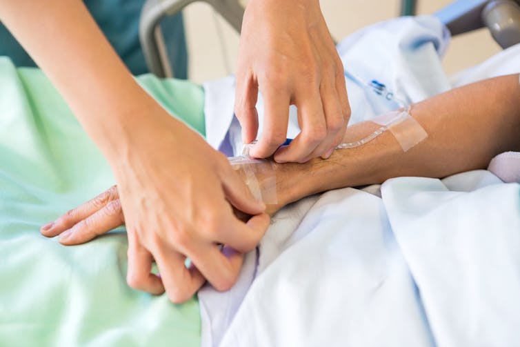 Un professionnel de santé pose une intraveineuse sur la main d’un patient