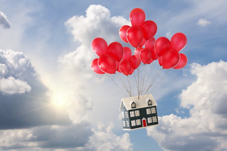 A house attached to red balloons floating up through clouds.