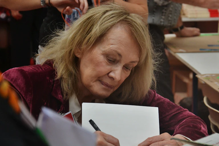 Una mujer firma libros en una feria del libro.