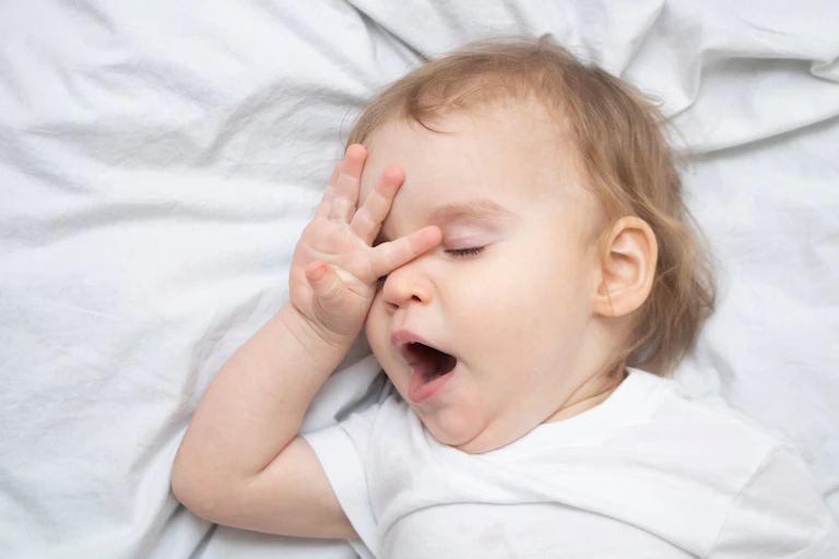 A one-year old yawns trying to sleep.