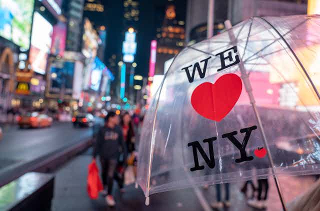 A transparent umbrella printed with "We [heart] NY" in Times Square, New York.