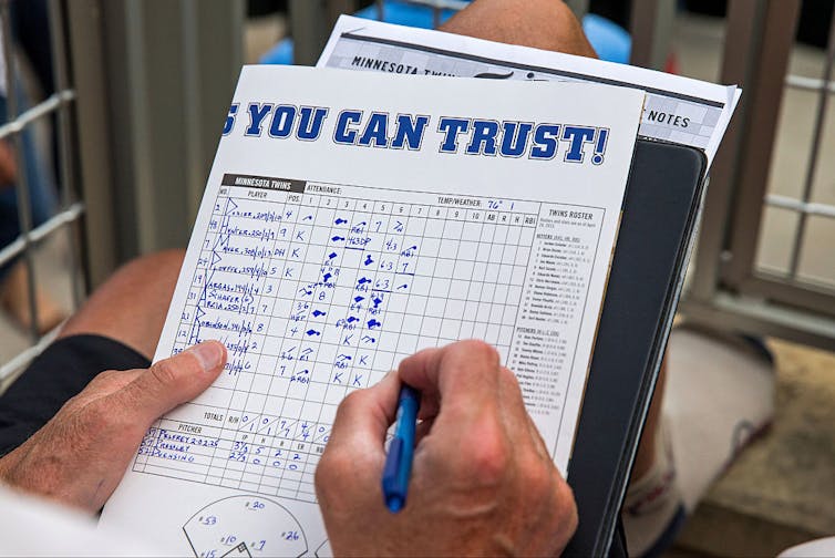 Baseball fan writes in a scorebook.