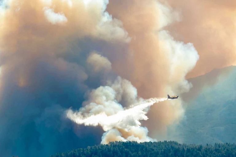 Un avión echa su carga de agua sobre un incendio.
