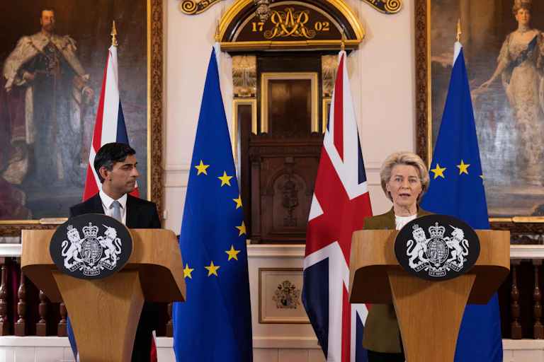 Two people stand behind matching lecterns with flags of the European Union and the United Kingdom behind them.