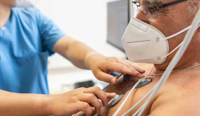 Close-up of a doctor attaching electrodes on patient's chest to monitor electrocardiogram in clinic.