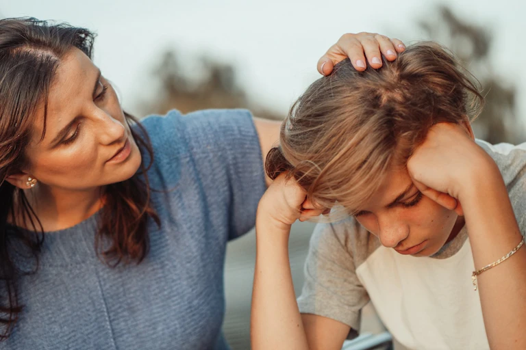 Mum reassuring worried teenage son by placing hand on head